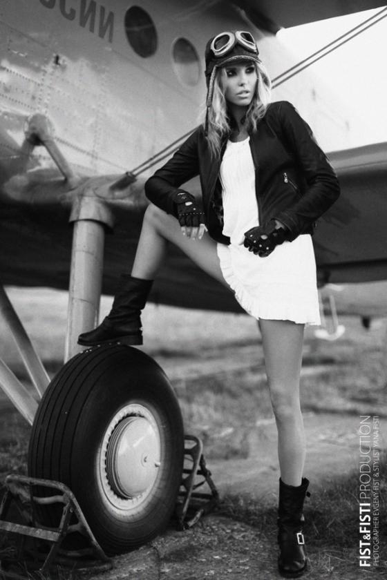 Черное-белое фото девушка в авиаторской шляпе рядом с самолетом