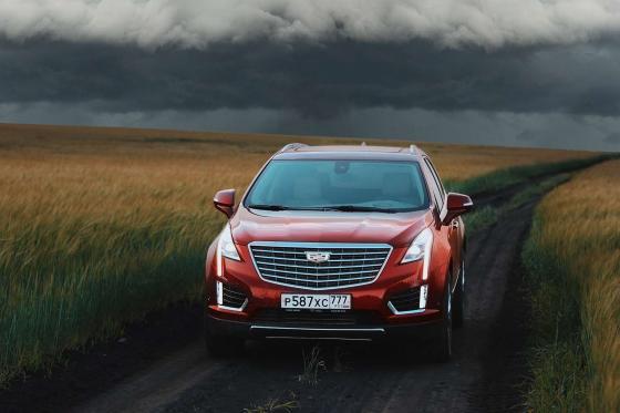 Cadillac XT5 на фоне туч посреди поля