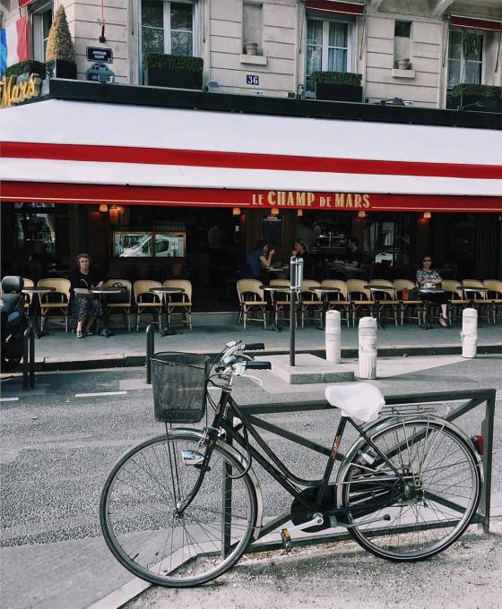 Узкая улочка в Париже с кафе и велосипедом 